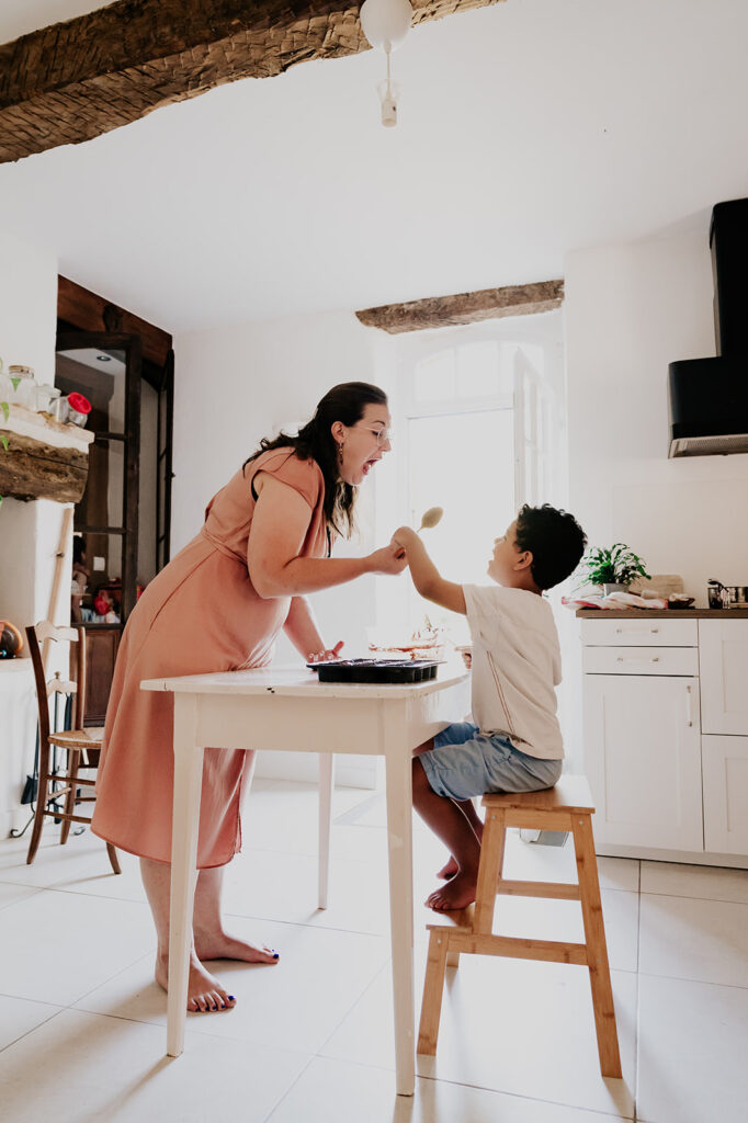 une maman et son fils dans la cuisine se chamaillent pour lecher la cuillere