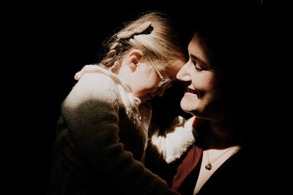 Calin maman et sa fille. lumiere magique qui les illumine, le reste est dans l ombre.