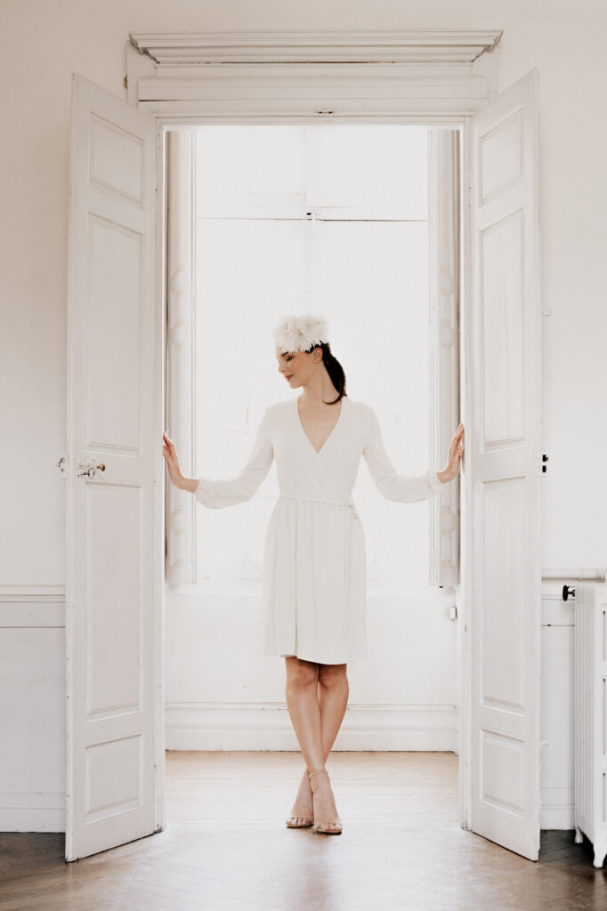 Femme en robe blanche Delphine Josse, captée par les photographes céline et Thibaut Deligey dans un une pose montrant l' élégance et minimalisme.