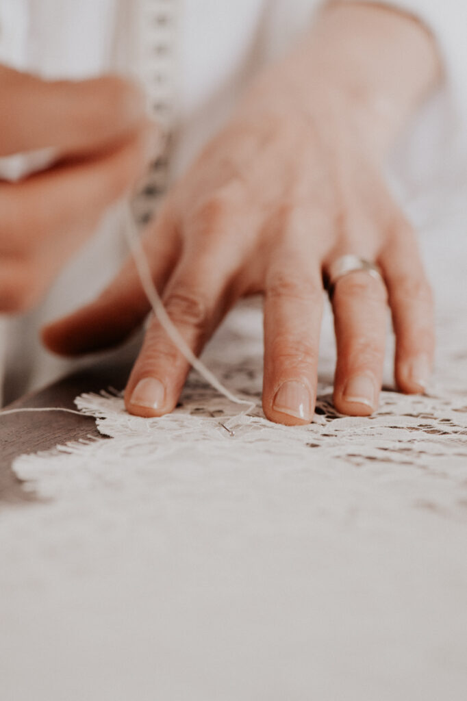 Gros plan sur une main en train de coudre de la dentelle, photo artisanat et savoir-faire textile