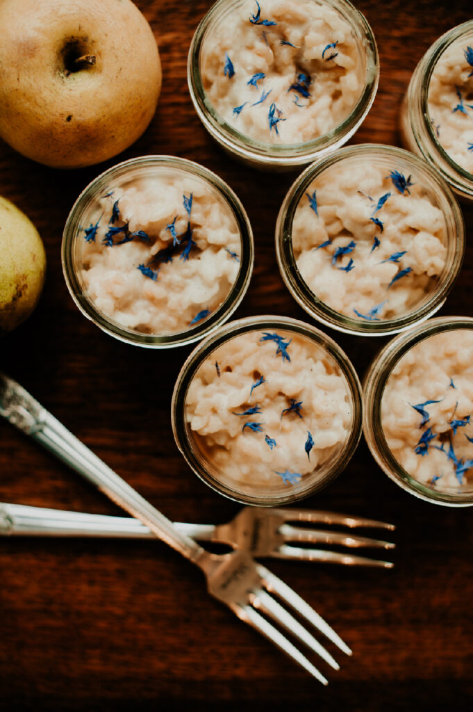 Gros plan sur des desserts crémeux présentés en petits pots, décorés de fleurs séchées bleues.