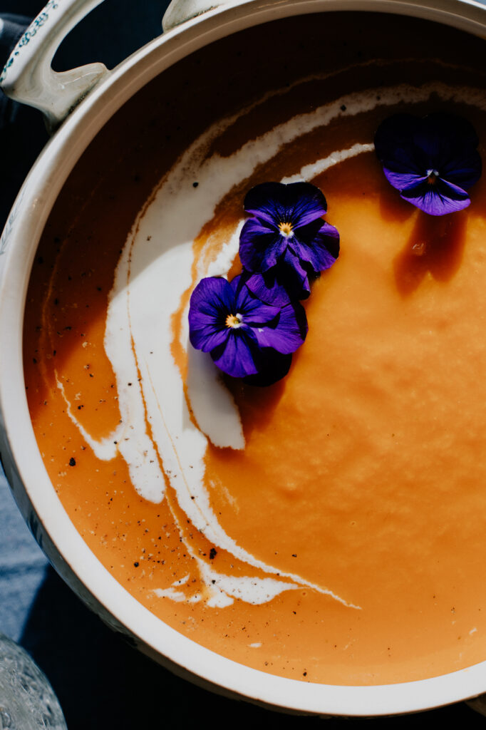 Gros plan de photo culinaire à toulouse. Soupe au potiron décoré de violettes
