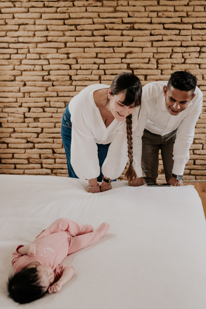 un couple regarde leur bébé dormir sous le regard bienveillant de Céline Deligey, photographe de familles à toulouse.