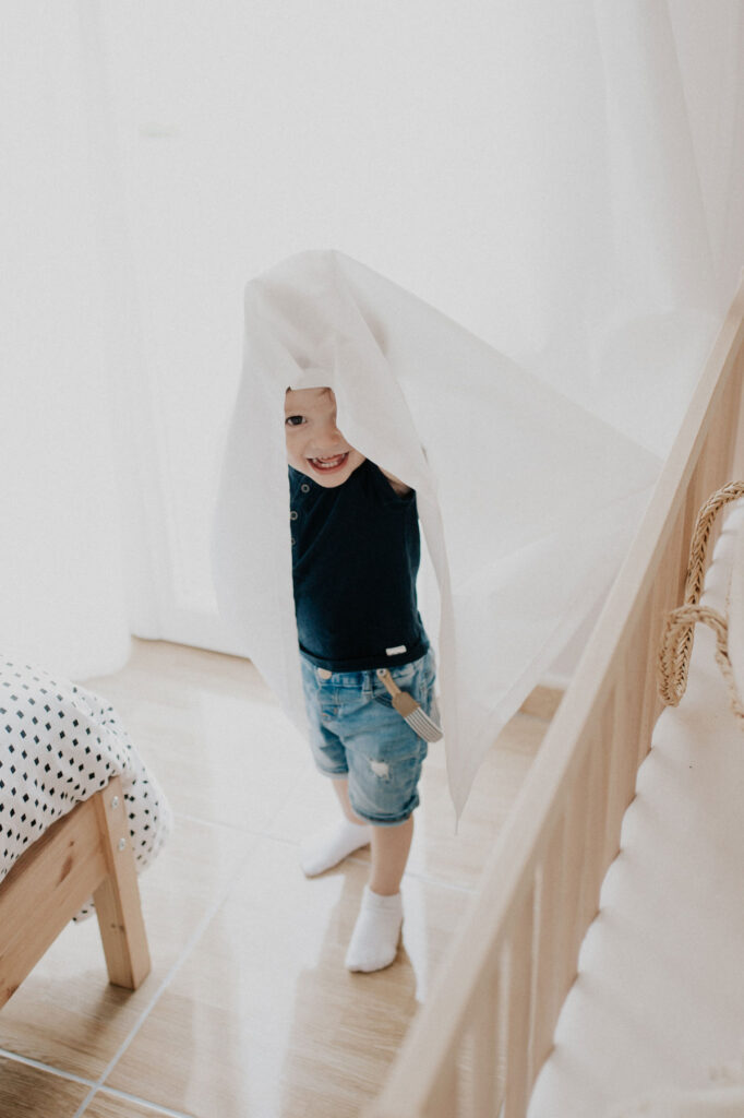 un enfant se cache sous le rideau. scene d'enfance typique.