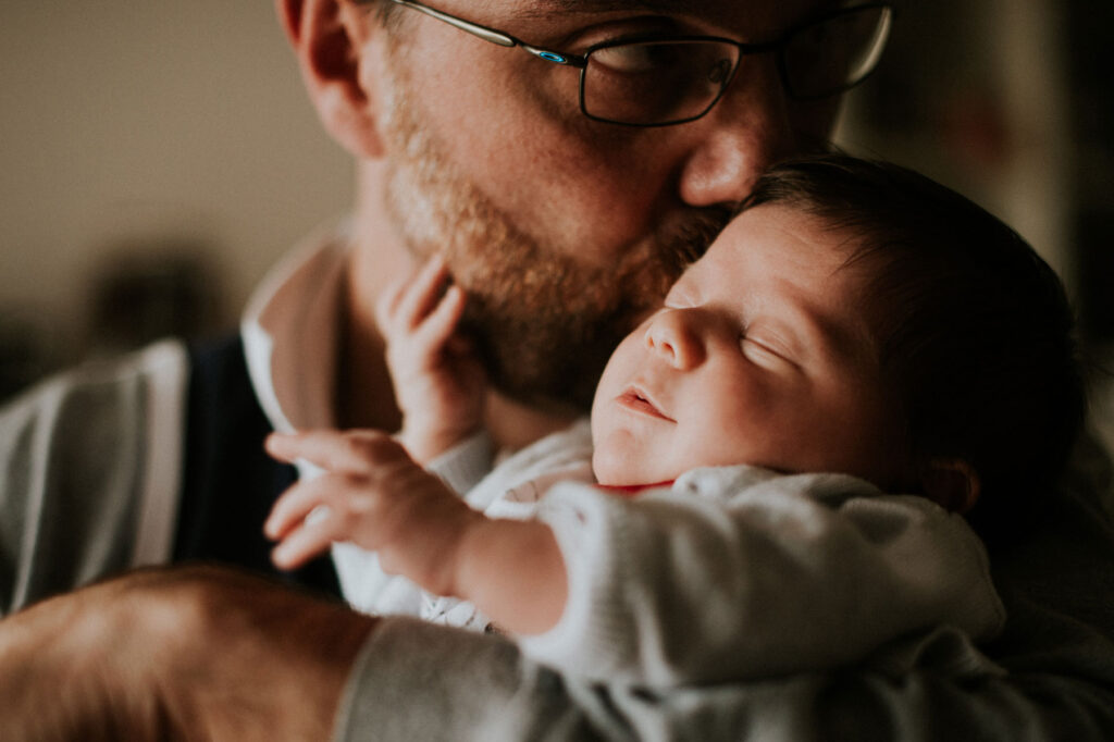 calin pere bébé. le bébé tend sa petite main pour toucher son papa.