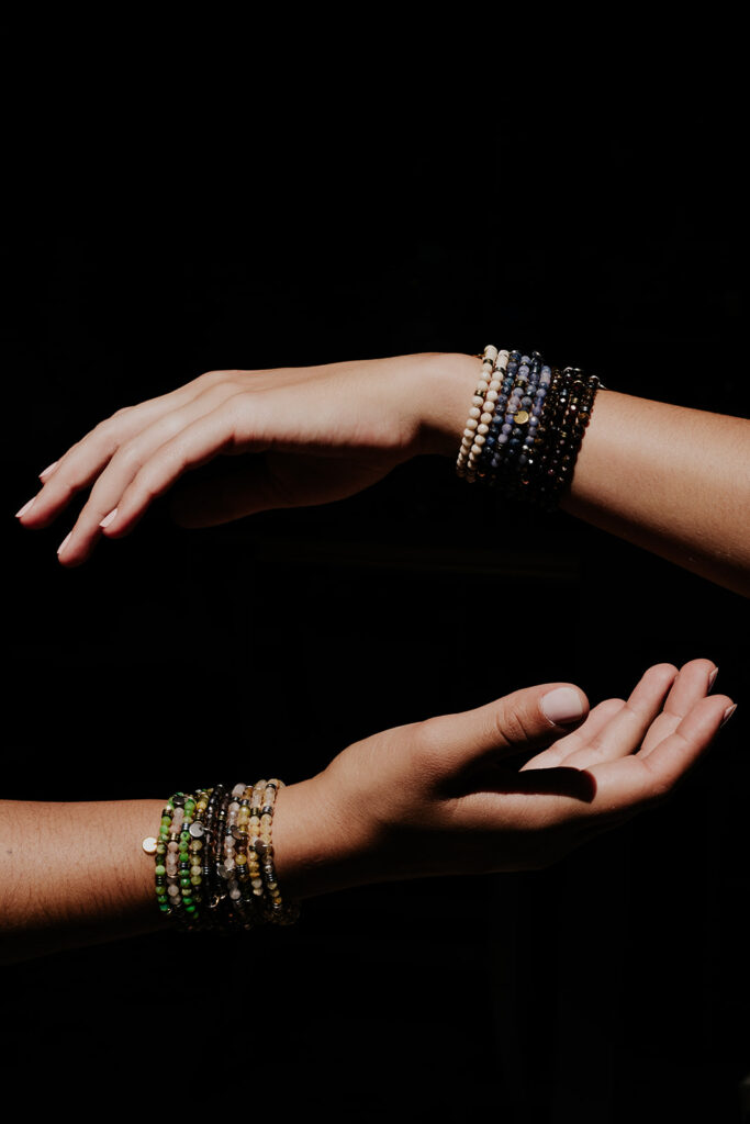 Photographie éditoriale d’artisanat à Toulouse – gros plan artistique sur deux mains portant des bracelets faits main, mise en valeur du geste et du savoir-faire.