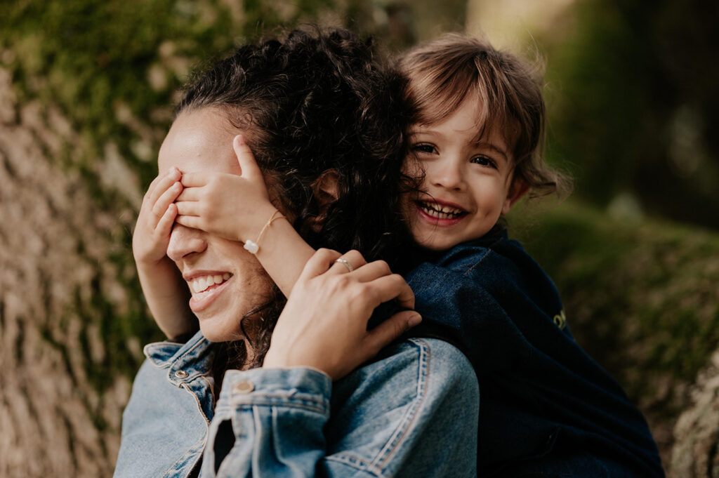 photographe famille toulouse . Une maman et sa fille qui lui cache les yeux. les deux sont souriantes et naturelles