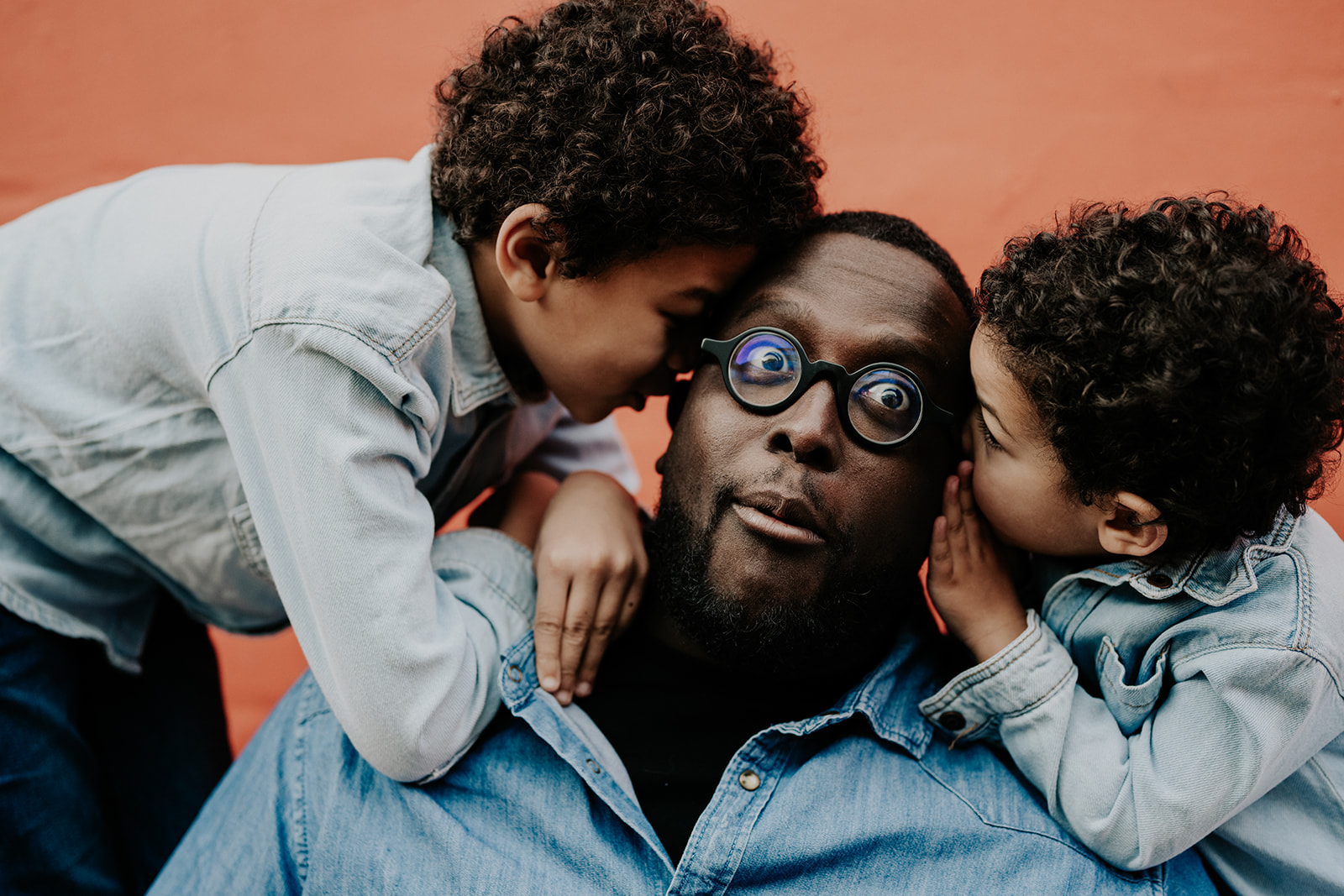 Un dimanche matin en famille. le papa fait le clown entouré de ses deux garçons.