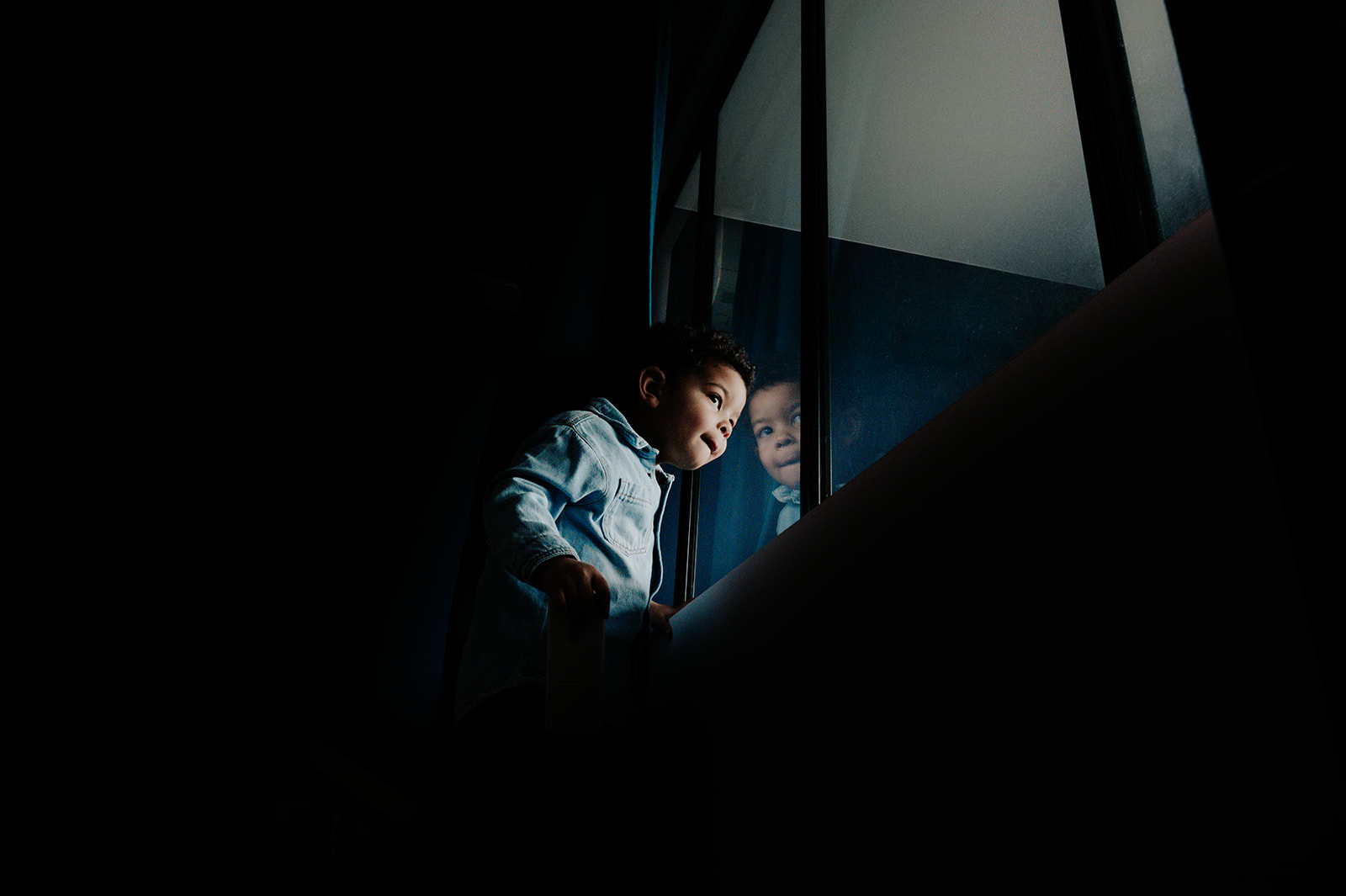 PETIT GARÇON QUI REGARDE PAR LA FENETRE. PHOTOGRAPHIE ARTISTIQUE DE FAMILLE
