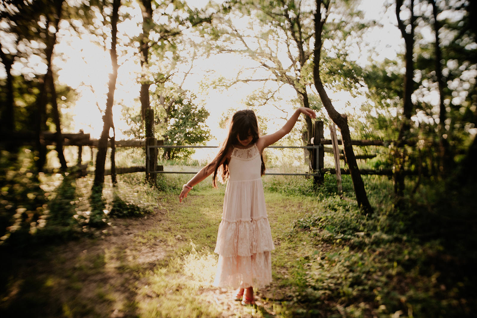 une petite fille en robe joue dans la lumière du soir