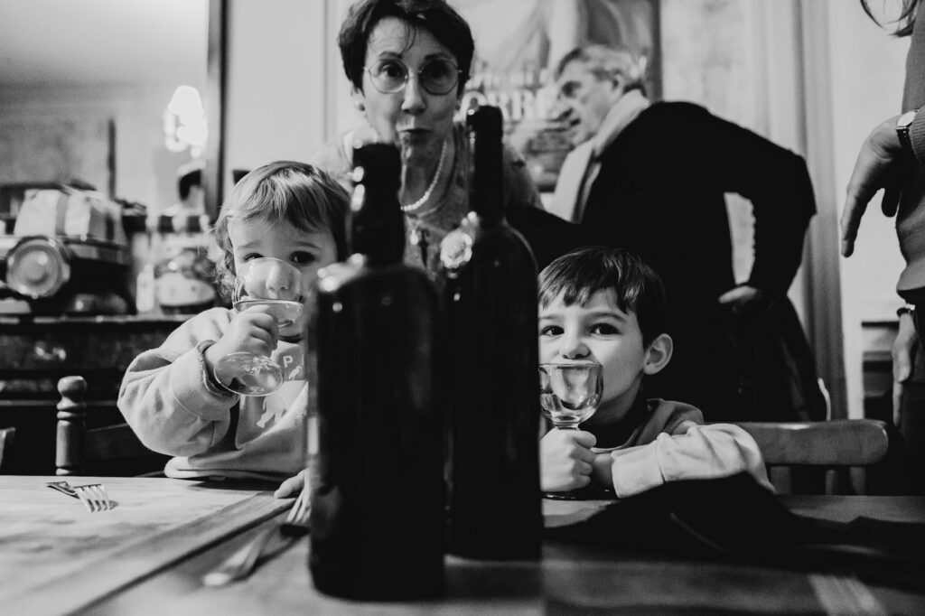 deux enfants boivent une grand mere les regarde. composition originale dans un restaurant par Céline Deligey photographe famille à Toulouse