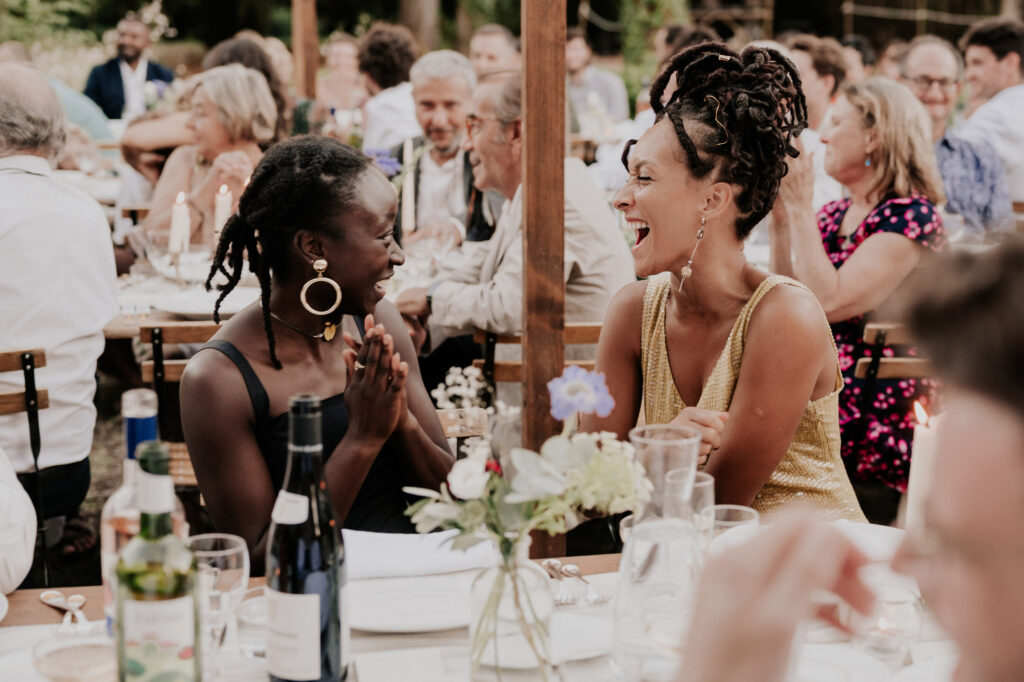 2 femmes riant aux éclats lors d’un mariage en extérieur, instant de complicité capté par photographe mariage Toulouse.