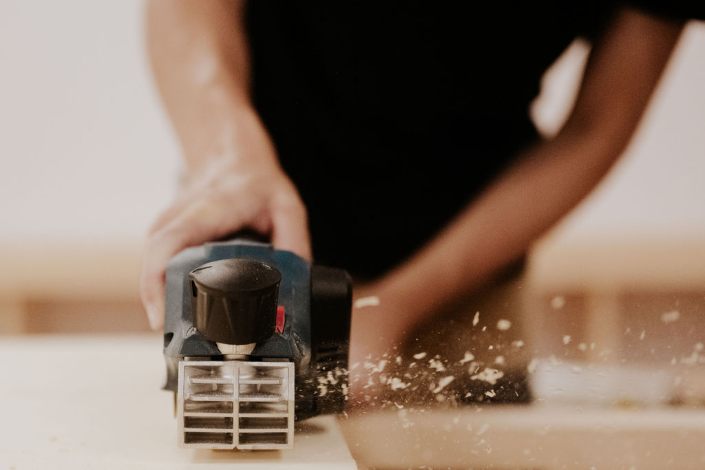Artisan menuisier travaillant le bois, copeaux et sciure en mouvement