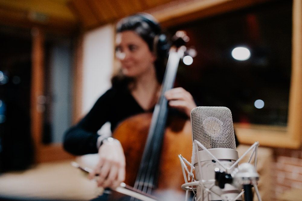 la violoncelliste apparait floue derriere le micro qui l'enregistre