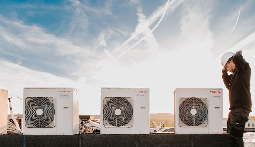 Technicien installe climatisation sur toit avec unités extérieures Toshiba