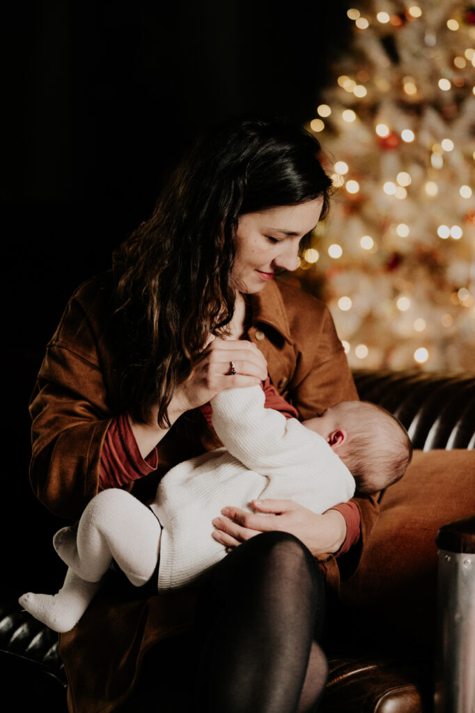 Reportage photo famille moment d'allaitement devant le sapin de noel